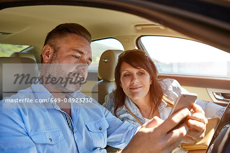 Couple in car, looking at smartphone