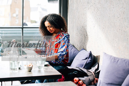 Mid adult woman using digital tablet in cafe