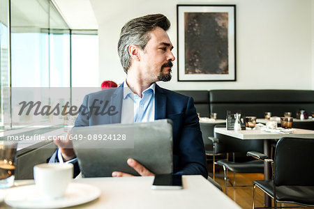 Businessman using digital tablet by restaurant window, London, UK