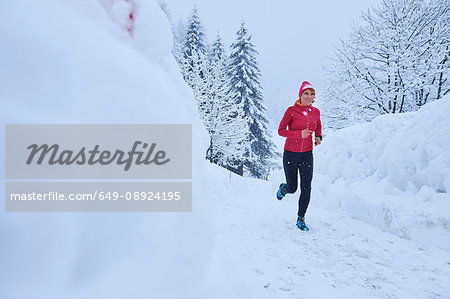 Female runner running on track in deep snow, Gstaad, Switzerland