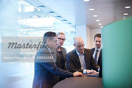 Businessmen and woman meeting around laptop in office