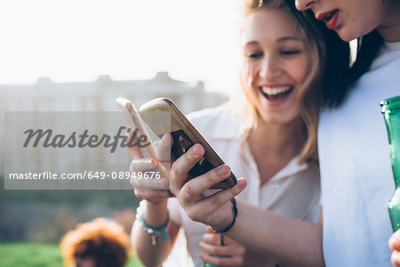 Two young women outdoors, looking at smartphones