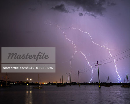 Lightning strikes over boats and power lines at the Indian River Lagoon off Cocoa, Florida