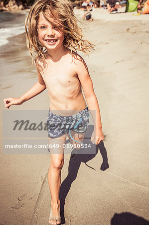 Young girl running on beach, smiling - Stock Photo - Masterfile