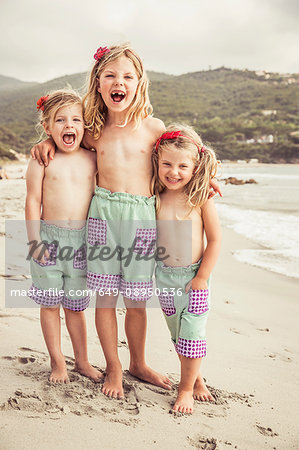 Portrait of three young sisters on beach, smiling Portrait of three young sisters on beach, smiling