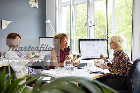 Three female designers having working lunch meeting in office