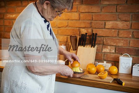 Senior adult woman squeezing oranges