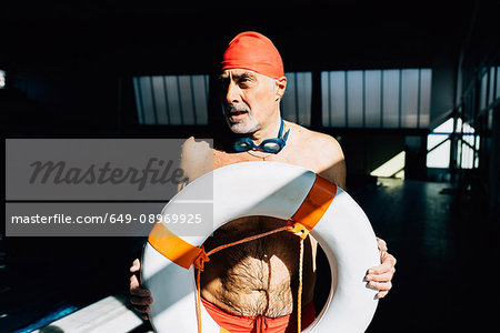 Senior man on lifeguard duty holding float