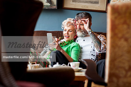 Quirky vintage couple looking at smartphone in tea room