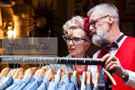 Quirky vintage couple looking at clothes rail in antiques and vintage emporium