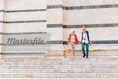 Tourist couple moving down Siena cathedral stairway, Tuscany, Italy