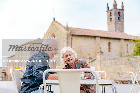 Tourist couple looking at smartphone at sidewalk cafe, Siena, Tuscany, Italy