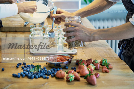 Two chefs preparing berry desserts, mid section