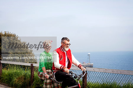 Quirky couple sightseeing on tandem bicycle, Bournemouth, England