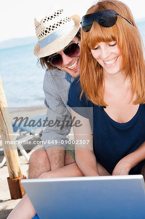 Couple at beach typing on computer