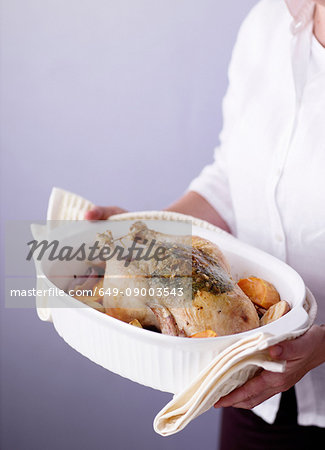 Woman holding dish of roast chicken