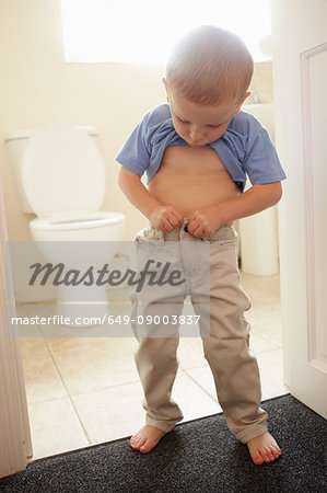 Boy buttoning his pants in bathroom