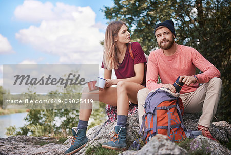 Couple hiking, sitting on rocks holding enamel mugs, Krakow, Malopolskie, Poland, Europe
