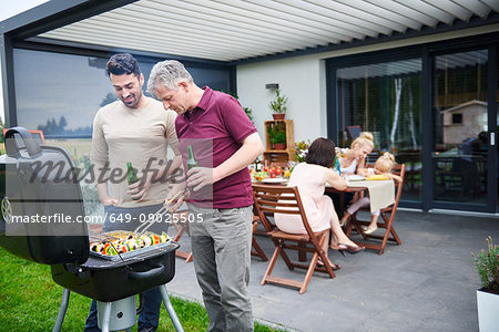 Mature and mid adult man barbecuing at family lunch on patio