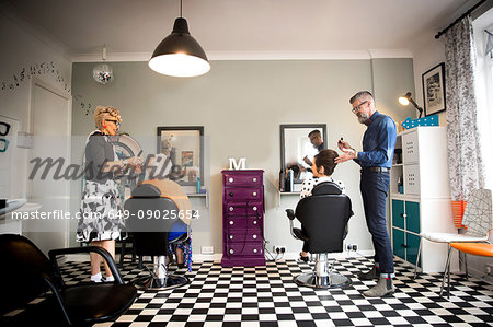 Couple in vintage clothes working on customers in quirky hair salon