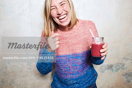 Portrait of woman holding smoothie, laughing