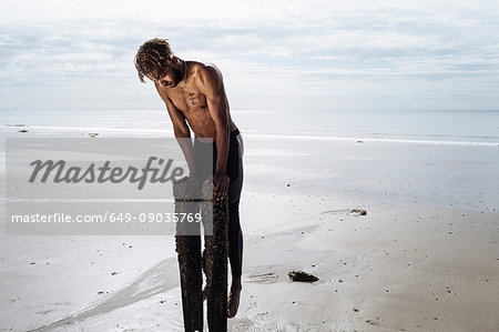 Young man training, doing push ups on wooden beach posts