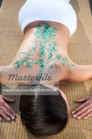 Woman in spa environment, relaxing with salt crystals on her back