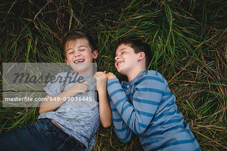 Brothers lying on grass together