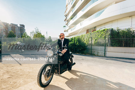 Portrait of mature businessman outdoors, sitting on motorcycle