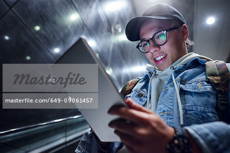 Young man moving down underground station escalator  looking at digital tablet