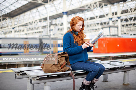 Woman on bench on train station platform, London