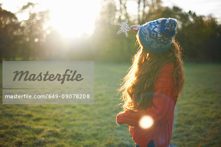 Young woman in rural setting, holding star up towards sunlight