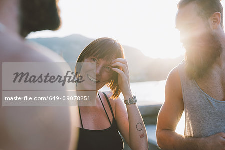 Three young hipster friends chatting on waterfront, Lake Como, Lombardy, Italy