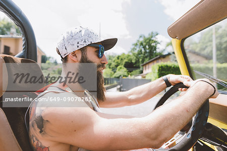 Young male hipster driving off road vehicle on road trip, Como, Lombardy, Italy