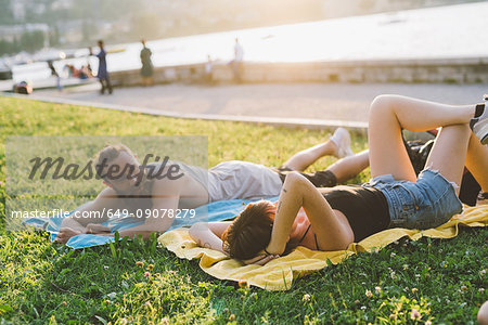 Young couple relaxing on waterfront grass, Lake Como, Lombardy, Italy