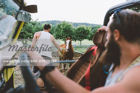 Young man on road trip feeding horse by roadside, Como, Lombardy, Italy