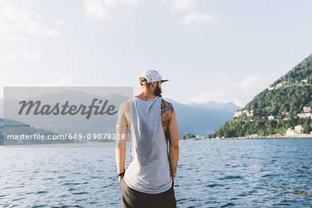 Rear view of young male hipster looking out from waterfront, Lake Como, Lombardy, Italy