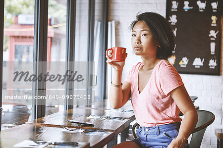 Woman in cafe watching from window seat, Shanghai French Concession, Shanghai, China