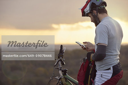 Male mountain biker looking at smartphone moorland Male mountain biker looking at smartphone moorland
