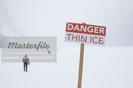 Danger sign and people on frozen Lake Louise, Canada