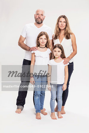 Studio portrait of mature couple with two daughters, full length