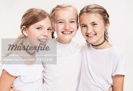 Studio portrait of three girls with blond hair, waist up