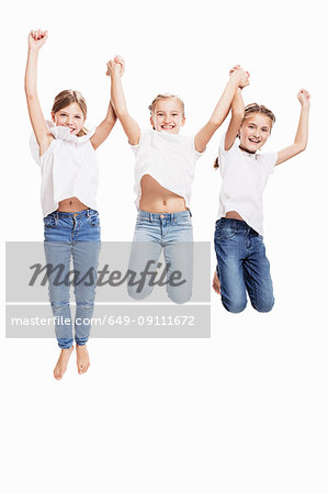 Studio portrait of three girls jumping mid air