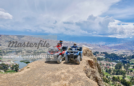 Mother and sons on top of mountain, using quad bikes, La Paz, Bolivia, South America