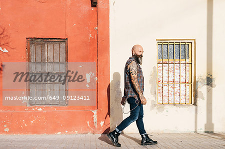 Mature male hipster walking along sidewalk