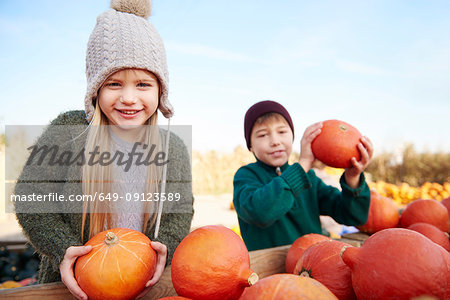 Girl and her brother holding harvested pumpkins