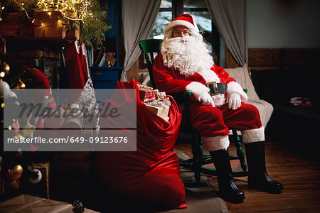 Portrait of Santa Claus, sitting in chair with sack full of presents