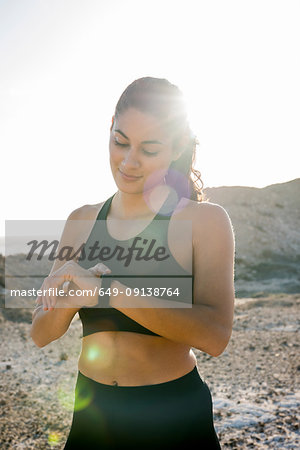 Young female runner checking smartwatch near coast, Las Palmas, Canary Islands, Spain