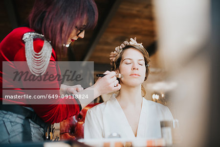 Bride preparing for wedding with make-up artist