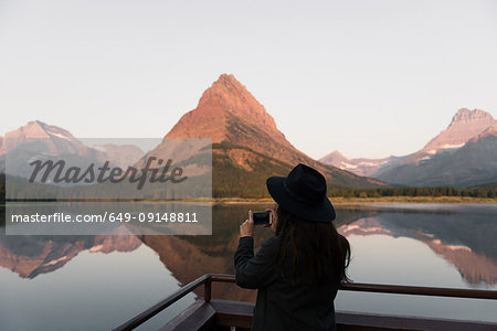 Woman taking photograph, Swiftcurrent Lake, Glacier National Park, Montana, USA